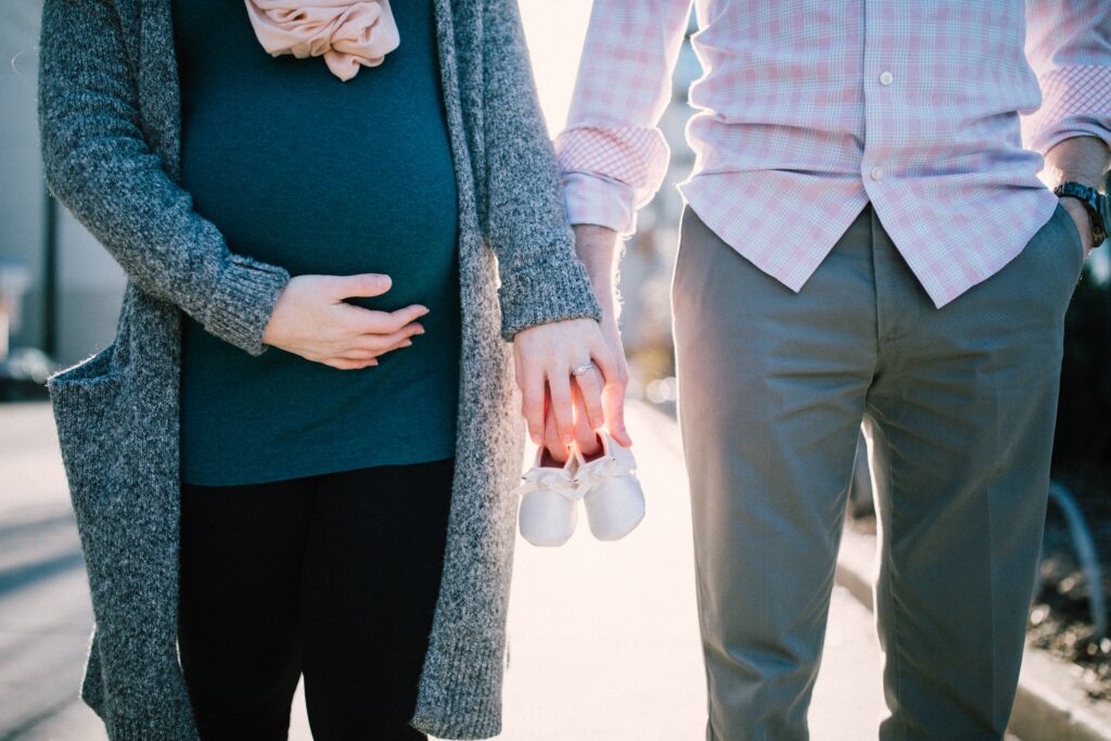 kobieta w ciąży i mężczyzna trzymający buciki niemowlęce